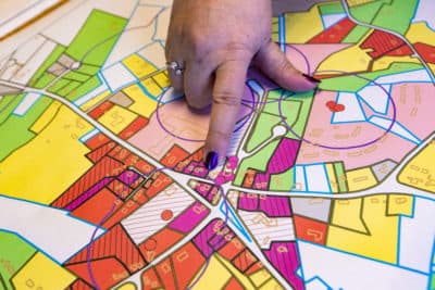 Town Administrator Denise Dembkoski points out on a map the origin of the PFAS contamination at the old fire station across the street from town offices. (Jesse Costa/WBUR)