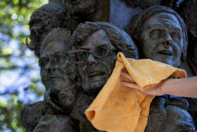 Faces on sculptor James Tyler's &quot;Tower of East Cambridge Faces&quot; get dried, as part of a routine cleaning by Cambridge Arts conservation technicians. (Robin Lubbock/WBUR)