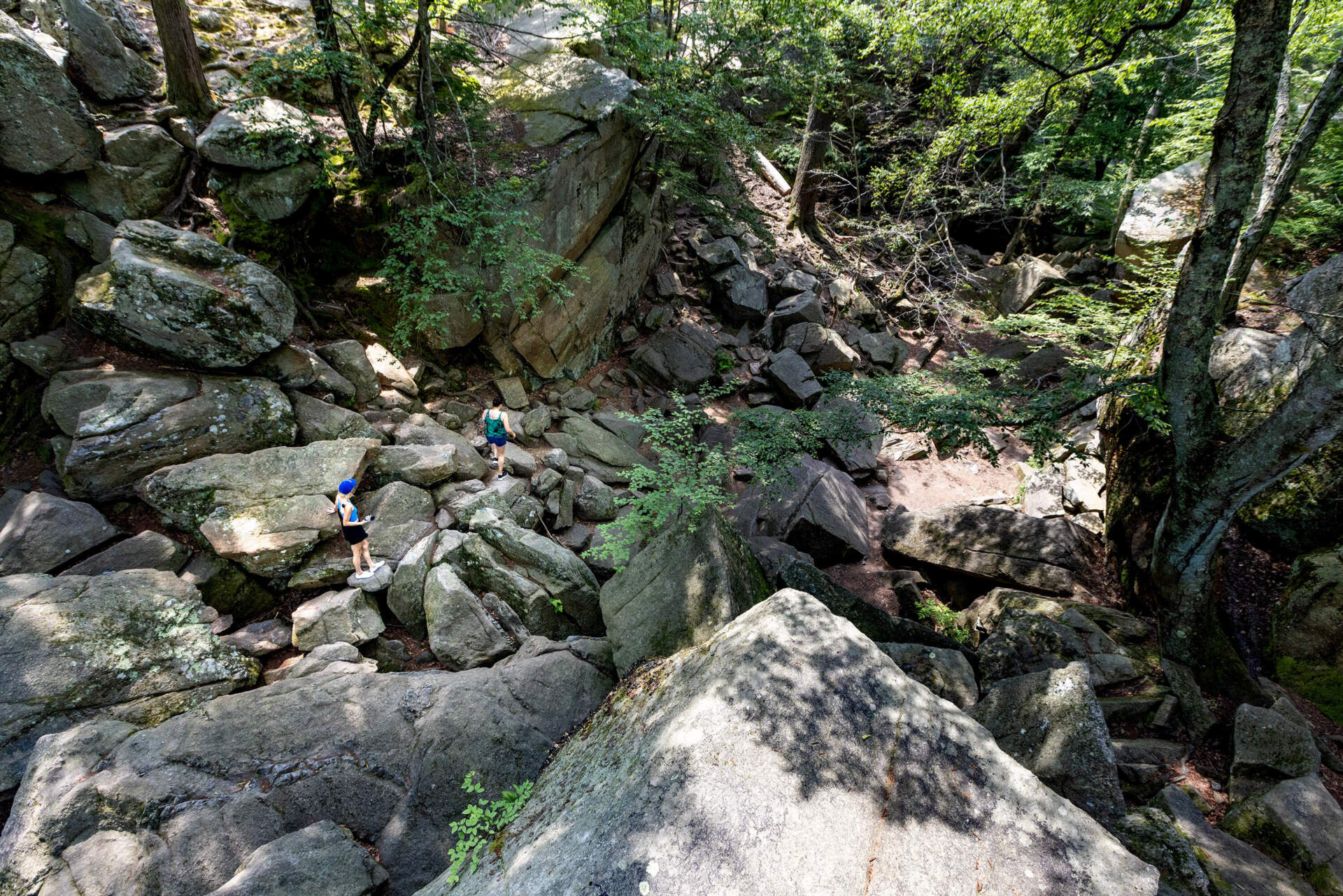 Two people walk through Purgatory Chasm in Sutton on a very hot day. (Jesse Costa/WBUR)