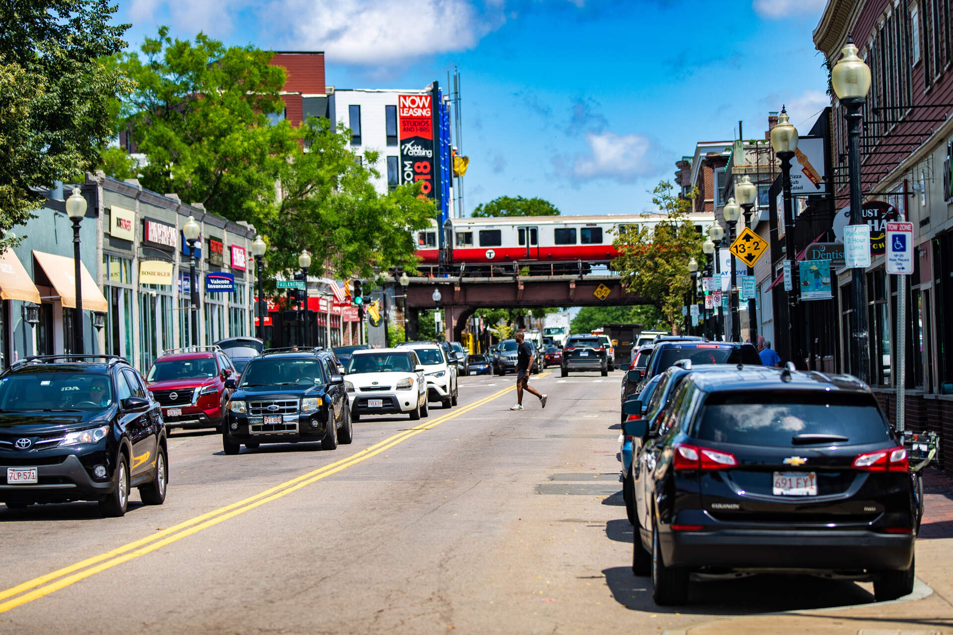 A man crosses a bustling Dorchester Avenue in Fields Corner at midday. (Jesse Costa/WBUR)