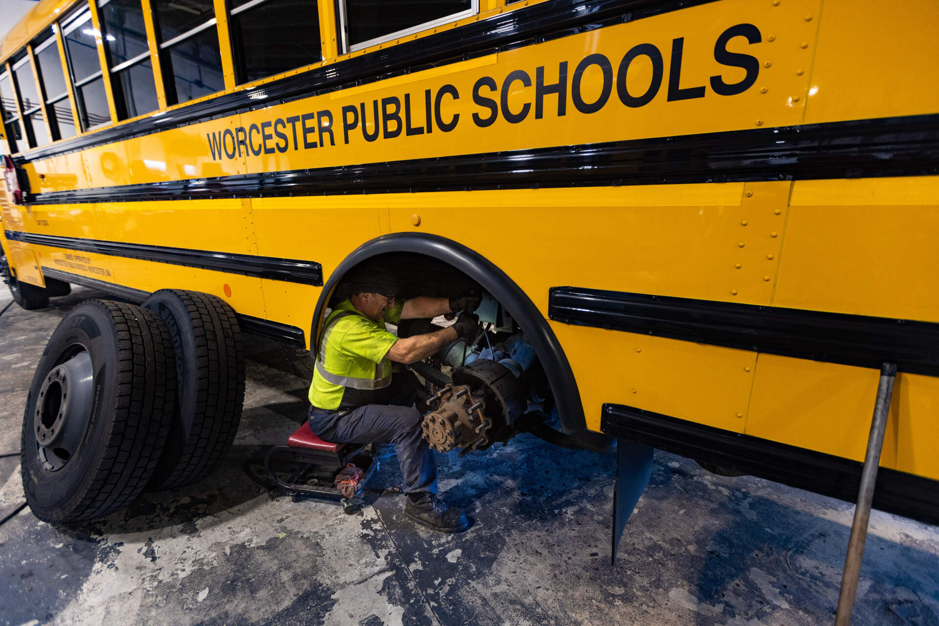 Mechanic Jani Nakollari performs a brake job on a Worcester school bus during summer maintenance readying it for the next school year. (Jesse Costa/WBUR)