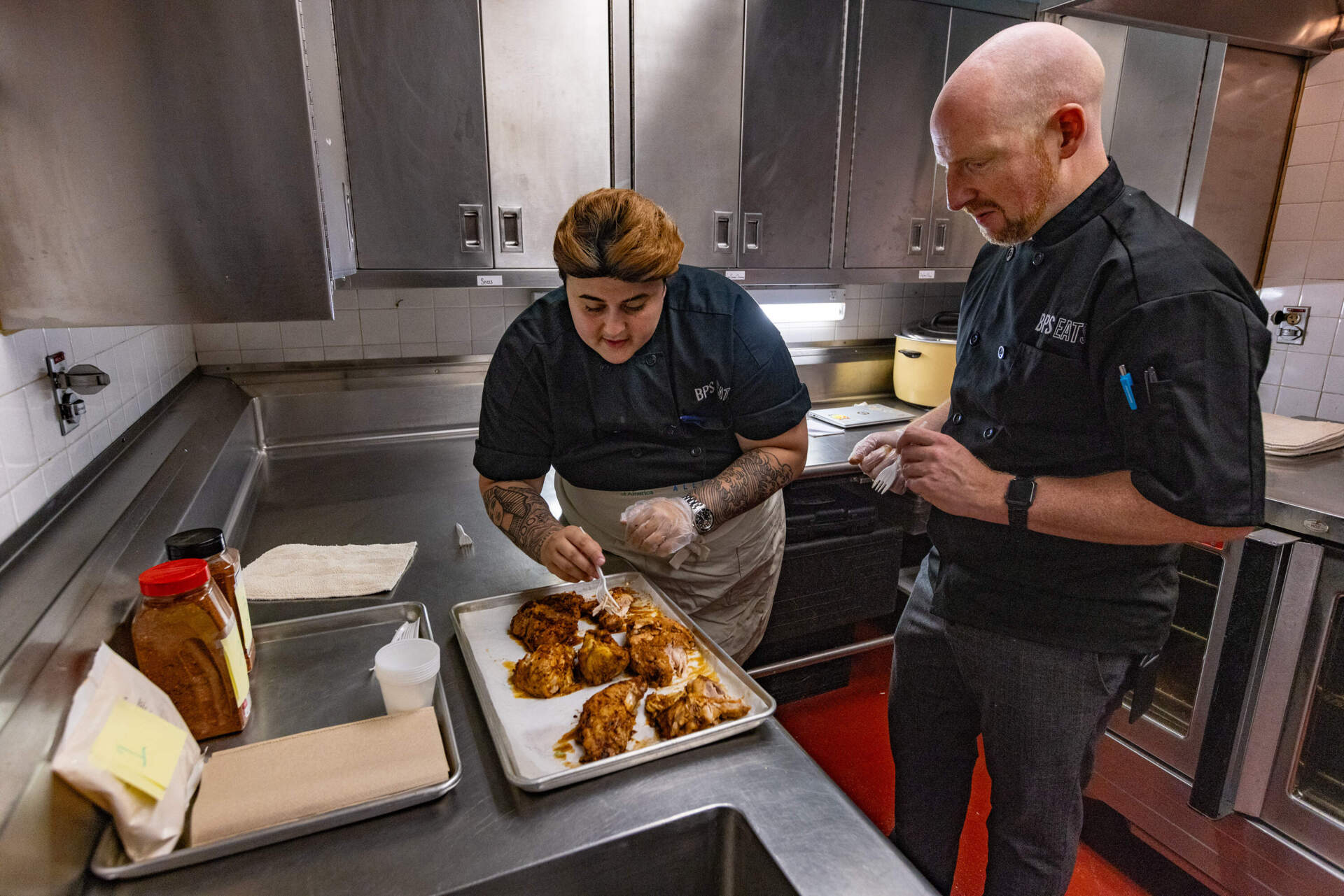 During a blind taste test inside a Boston Public Schools' kitchen, chefs Alexis Assad and Andrew Urbanetti dig into chicken seasoned with three taco spice blends without a lot of salt. (Jesse Costa/WBUR)