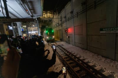 Riders use their cellphones to document the first Green Line train as it arrives at Medford/Tufts Station. (Jesse Costa/WBUR)