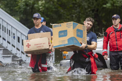 Savannah Fire Advanced Firefighters Ron Strauss, right, and Andrew Stevenson, left, carry food to residents in the Tremont Park neighborhood that where stranded in flooding from Tropical Storm Debby in Savannah. (Stephen B. Morton/AP)