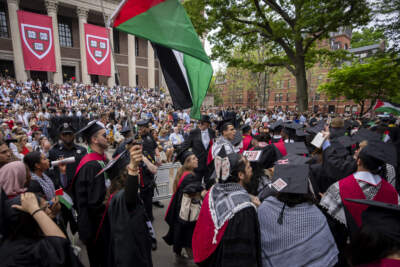 Graduating students hold Palestinian flags and chant as they walk out in protest over the 13 students who have been barred from graduating Harvard due to protest activities on May 23. (Ben Curtis/AP)