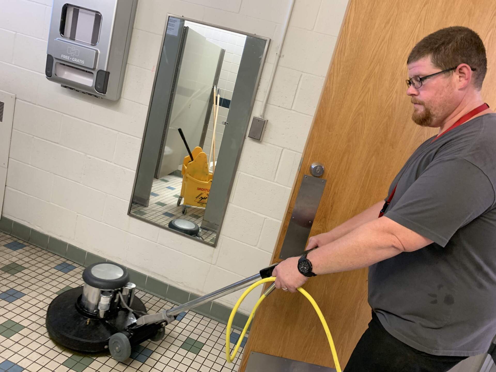 Custodian Tom Lowe uses a commercial floor scrubber to deep clean the bathrooms at Witchcraft Heights Elementary School in Salem. (Carrie Jung/WBUR)