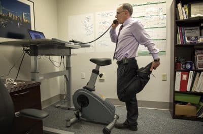 Dr. Eddie Phillips stretches as he talks on the phone at his office at the VA Boston Healthcare System. (Robin Lubbock/WBUR)